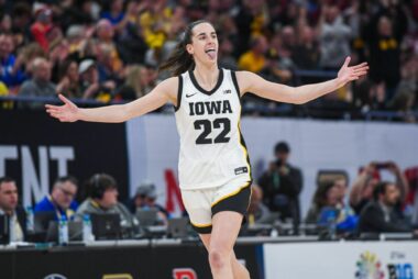 An image of Clark in her white Hawkeye's jersey with her hands out in a celebratory fashion.