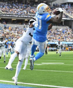 A picture of Mike Williams in a powder blue chargers uniform jumping into the air and making a catch over a jaguars defender in Los Angeles.