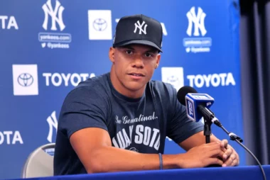 An image of Juan Soto at the podium of his introductory press conference for the Yankees. He is wearing a Yankees hat and T-shirt.